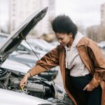 A pregnant woman fixing a car engine