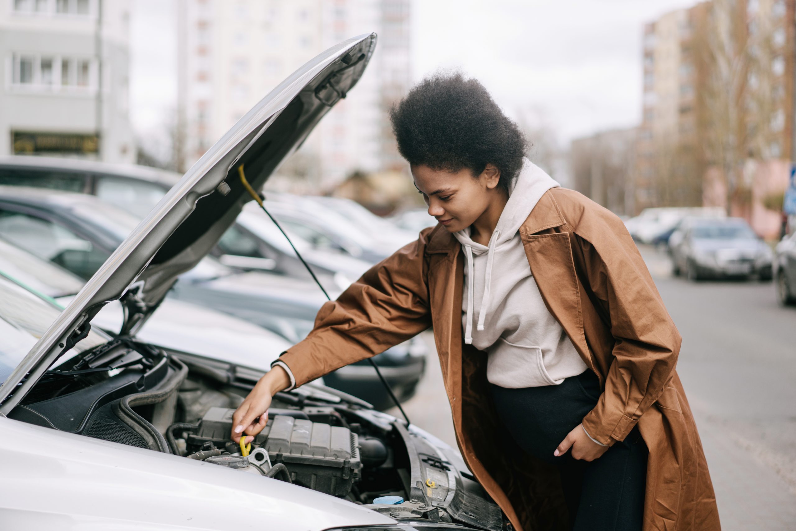 A pregnant woman fixing a car engine