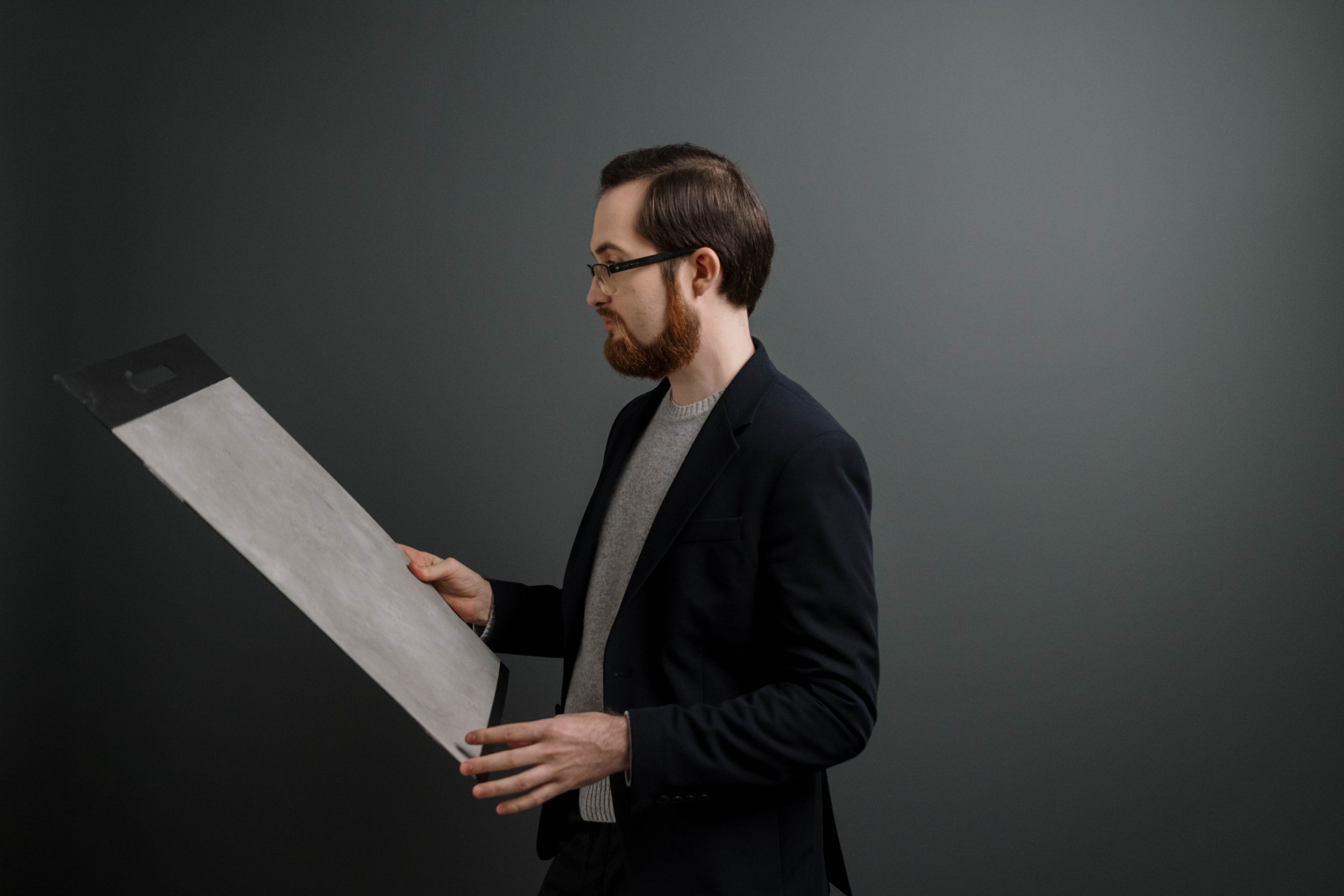 Man in black suit holding white paper