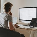 Man sitting in front of three computers